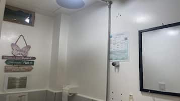 A bathroom with a shower, a toilet, and a mirror. There are motivational signs on the wall and a paper with text.