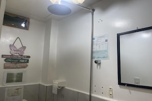 A bathroom with a shower, a toilet, and a mirror. There are motivational signs on the wall and a paper with text.