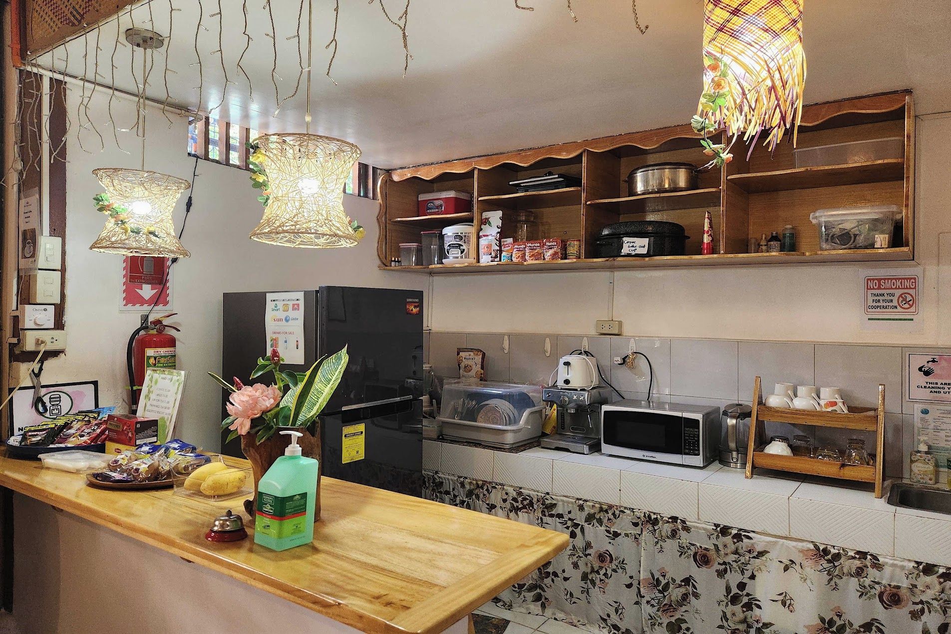 A kitchen with a refrigerator, microwave, and various food items on shelves.