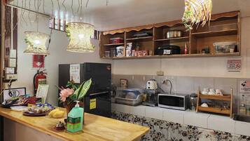 A kitchen with a refrigerator, microwave, and various food items on shelves.