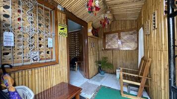 A room with a bamboo wall, a wooden bench, a chair, and a small table.