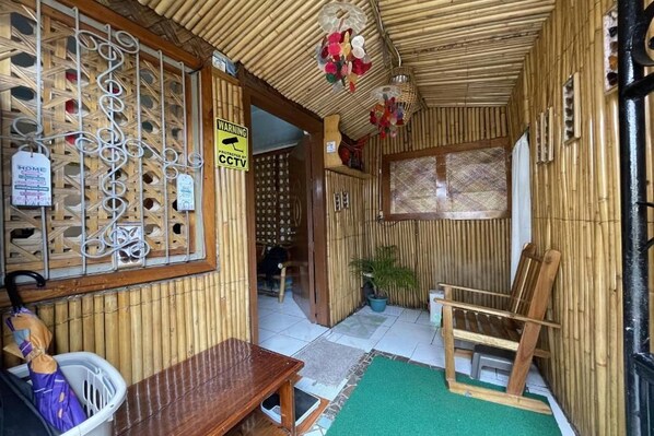 A room with a bamboo wall, a wooden bench, a chair, and a small table.
