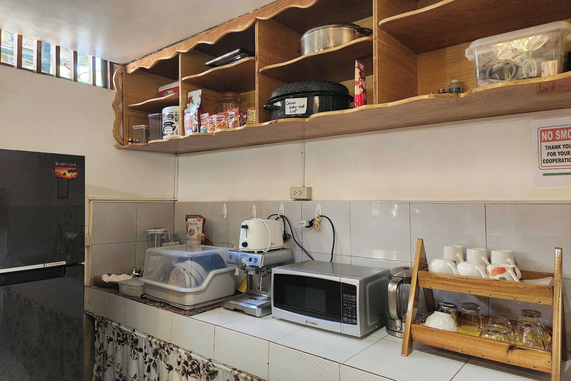 Une cuisine avec des étagères en bois, un réfrigérateur, un four à micro-ondes et une bouilloire.