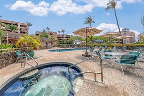 Ein Hotelpoolbereich mit Liegestühlen, Sonnenschirmen und einem Whirlpool.