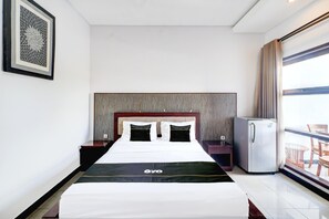 A hotel room with a bed, a nightstand, a refrigerator, and a window with curtains. - Luxury Deluxe DBL Escape W/ Free Wifi and Parking (Kedonganan)