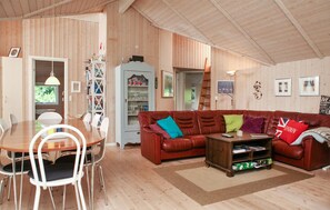 A cozy living room with a wooden ceiling, a brown leather sofa, a dining table with chairs, and a bookshelf. - Pet friendly home in Frørup with sauna (Frørup)