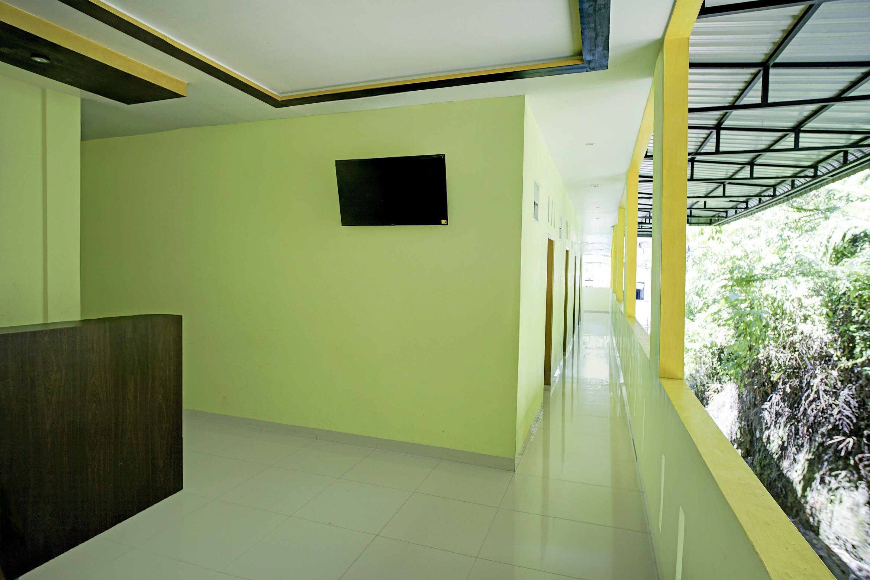 A corridor with a tiled floor, a reception desk, and a window with a view of greenery.