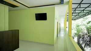 A corridor with a tiled floor, a reception desk, and a window with a view of greenery. - Cozy Twin Escape With Free Wifi and Parking (Parapat)