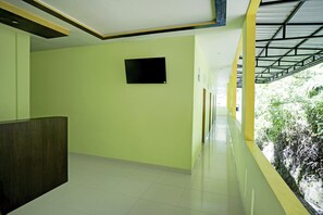 Corredor com piso de azulejos, balcão de recepção e janela com vista para área verde.
