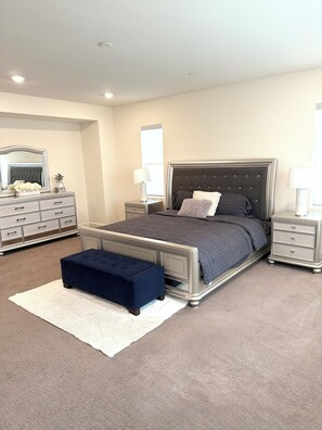 Une chambre à coucher avec un grand lit, des tables de chevet, une commode et un miroir.
