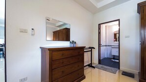 Um corredor com cômoda de madeira, espelho e porta para um banheiro.