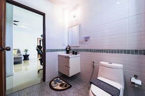 Casa de banho moderna com sanita, lavatório e espelho. Um tapete com motivos marítimos no chão.