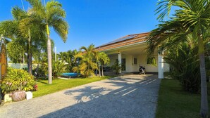 A house with a covered patio, a gravel driveway, and palm trees. - Cozy Luxury 2BR Pool Villa Retreat (PV1) (Hua Hin)