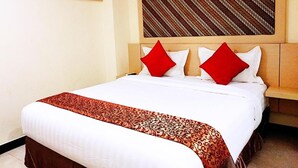 A hotel room with a bed, a headboard, and a wall-mounted artwork. - Jakarta City Hotel (Kec.Taman Sari)
