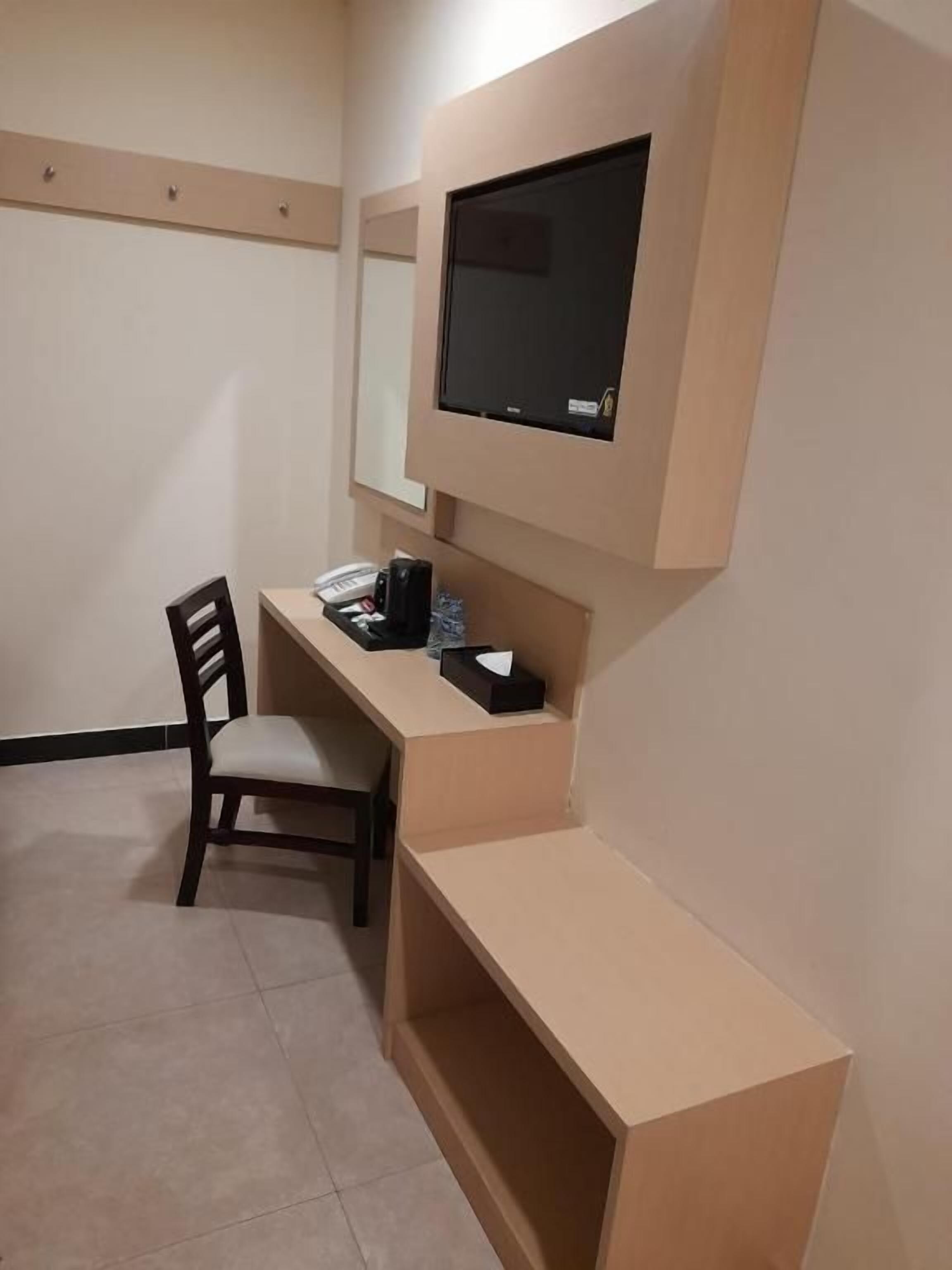 Una habitación pequeña con un escritorio, una silla y un televisor de pantalla plana montado en la pared.