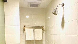 A small, tiled bathroom with a toilet, a towel rack, and a showerhead. - Jakarta City Hotel (Kec.Taman Sari)