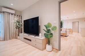 A modern living room with a flat-screen TV, a potted plant, and a sofa in the background.