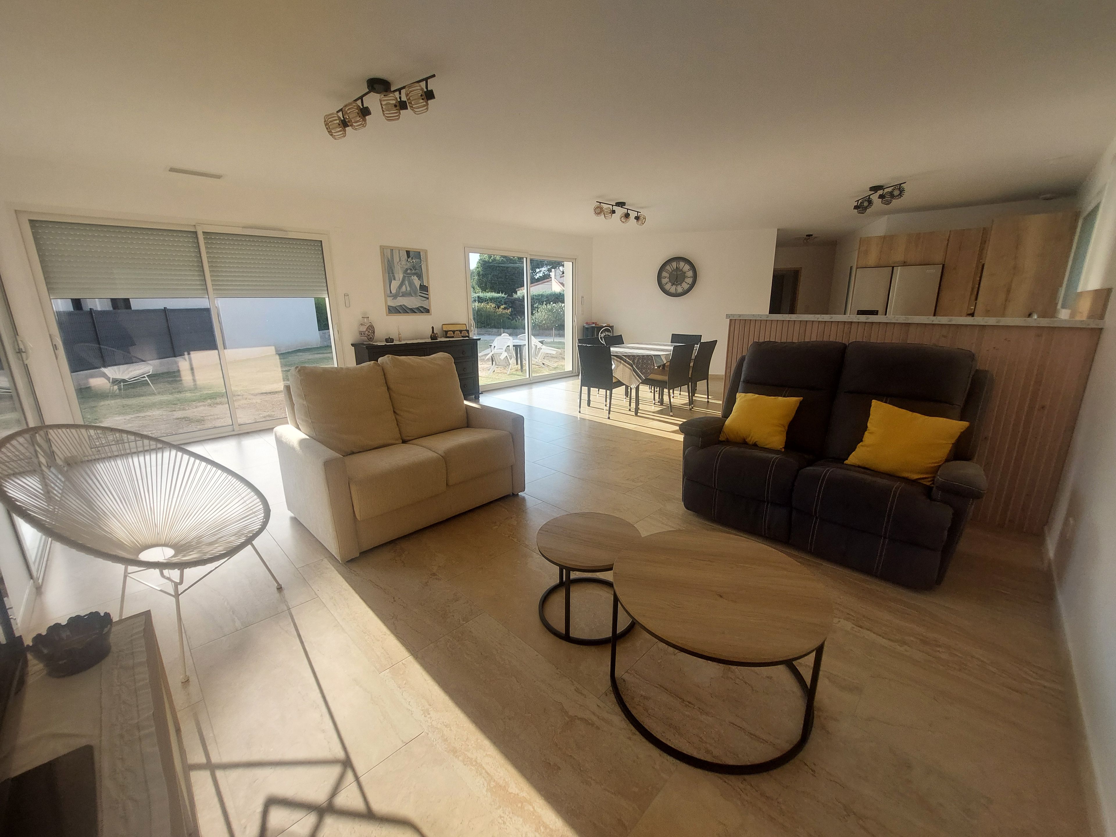 A spacious living area with a sofa, armchair, and a dining table.