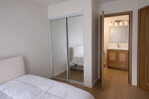 A bedroom with a bed, a sliding door closet, and a bathroom with a mirror and sink. - Newly Renovated Cozy bed and private bath with AC in beautiful San Diego (San Diego)