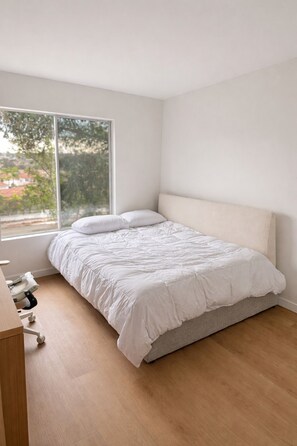 A bedroom with a bed, a window, and a wooden floor. - Newly Renovated Cozy bed and private bath with AC in beautiful San Diego (San Diego)