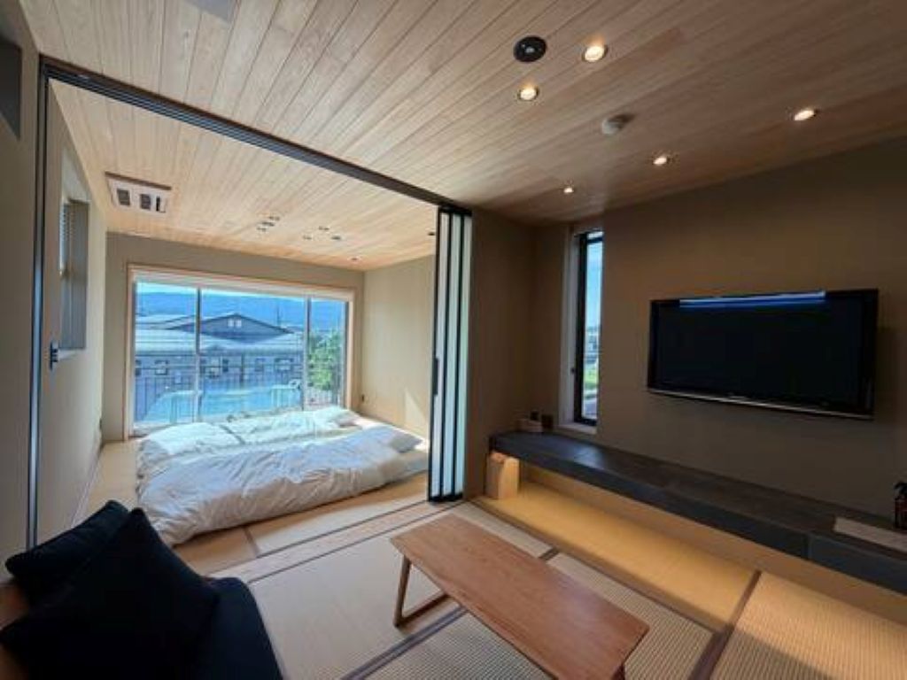 A modern bedroom with a large bed, a television, and a view of the outside.