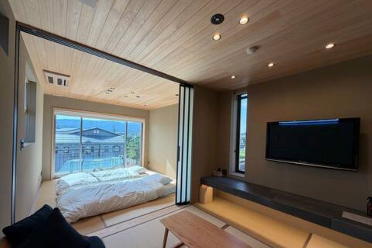 A modern bedroom with a large bed, a television, and a view of the outside.