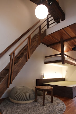 A loft-style room with a wooden staircase, a round table, and a built-in bench. - araijukuloop (Myoukou)