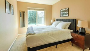 A bedroom with a bed, bedside tables, a window, and a door. - Comfortable Family Getaway ,Modern 3BR Home with AC & Quiet Neighborhood (Portland)