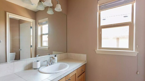 A bathroom with a white sink, a mirror, and a window. - Comfortable Family Getaway ,Modern 3BR Home with AC & Quiet Neighborhood (Portland)