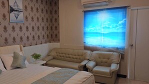 A bedroom with a bed, two armchairs, a small table, and a window with a view of the sea. - Jomtien Beach Stay (Pattaya)