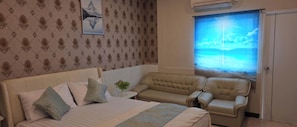 Un dormitorio con cama, dos sillones, una mesita y una ventana con vistas al mar.