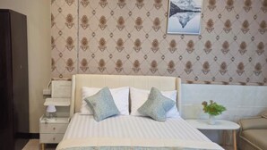 A hotel room with a bed, a nightstand, a dresser, and a sofa. - Jomtien Beach Stay (Pattaya)