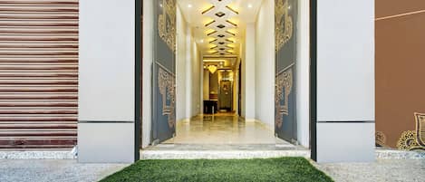A hallway with a patterned wall, a green carpet, and a ceiling with recessed lighting.