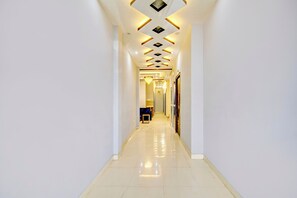 A long, narrow hallway with a reflective floor, leading to a room with a door at the end.