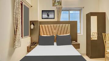 A bedroom with a bed, a bedside table with a lamp, a wardrobe, and a window with curtains.