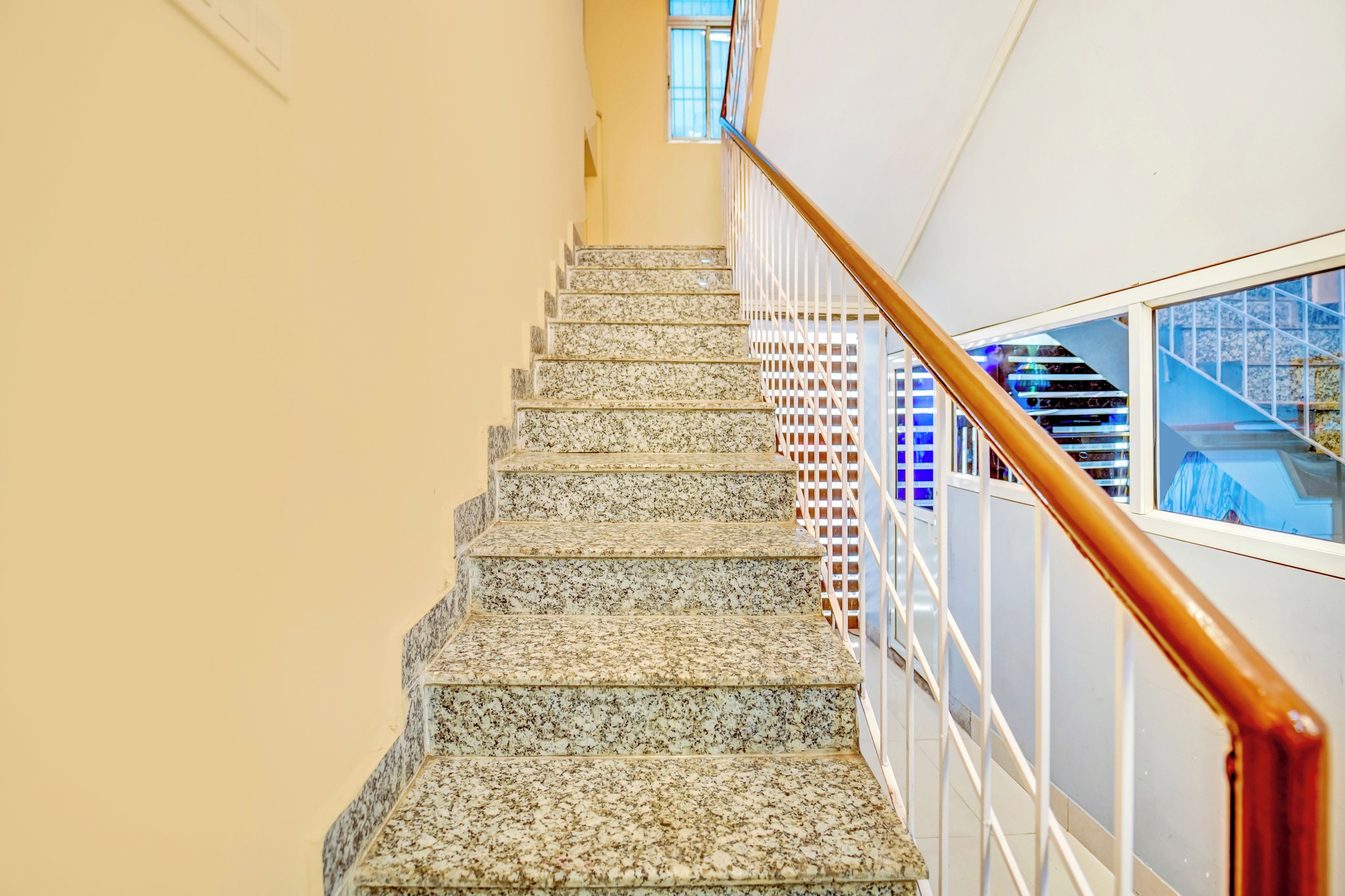 A staircase with a wooden handrail and a glass railing, leading to an upper floor.