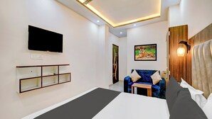 Una habitación de hotel moderna con una cama, un televisor de pantalla plana, un cuadro, un sofá y una lámpara fijada a la pared.