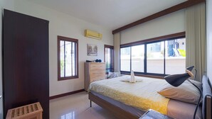 Une chambre d’hôtel équipée d’un lit, d’un bureau, d’une lampe, d’une commode et d’une fenêtre avec des stores.