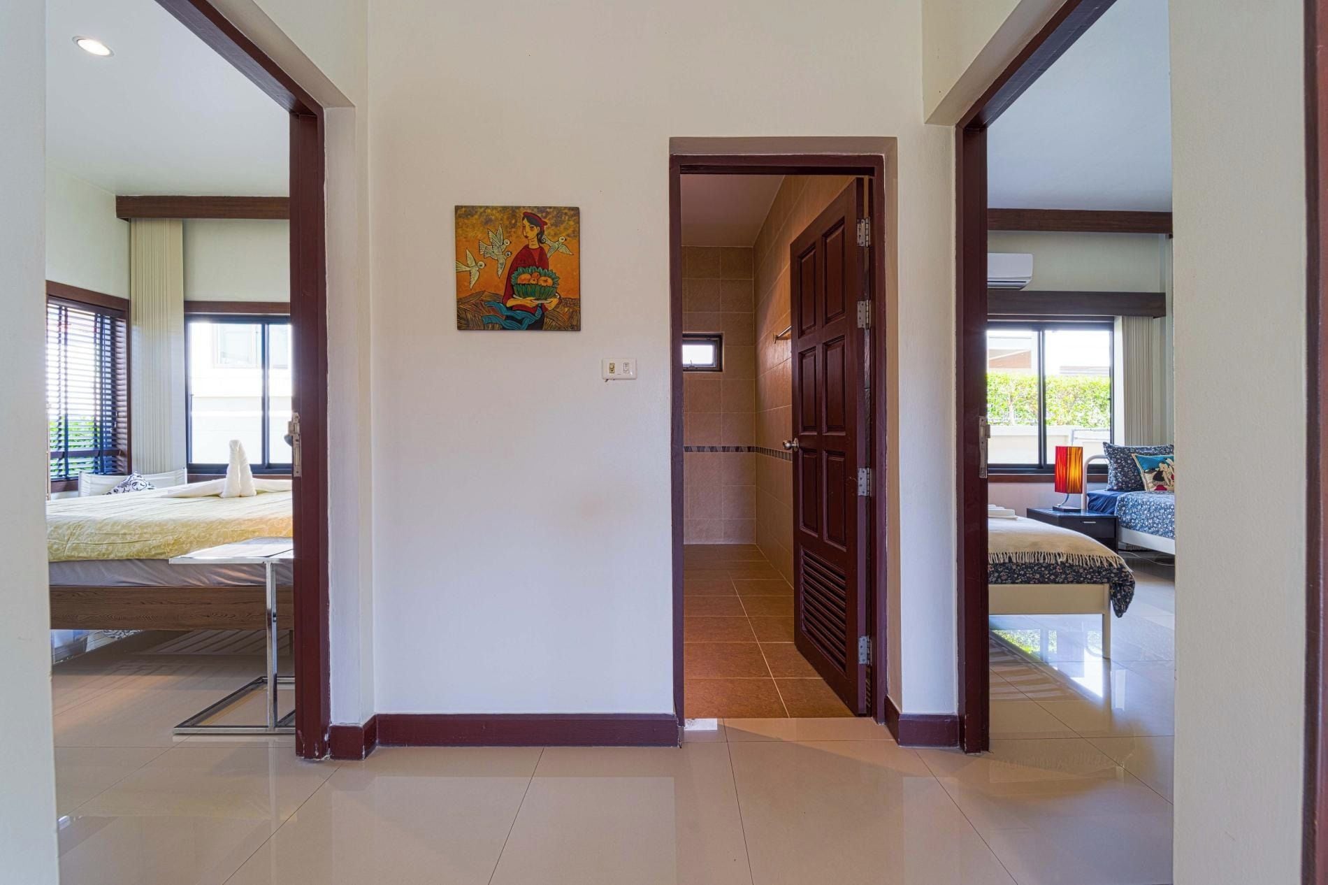 Corredor de hotel com uma cama, um quadro e um banheiro visível por uma porta aberta.