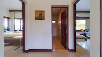 Corredor de hotel com uma cama, um quadro e um banheiro visível por uma porta aberta.