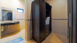 Une salle de bain avec un meuble en bois foncé, un lavabo avec un miroir et des murs carrelés.