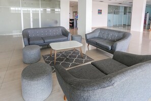 Un vestíbulo moderno con sofás grises, una mesa de centro blanca y una alfombra estampada.
