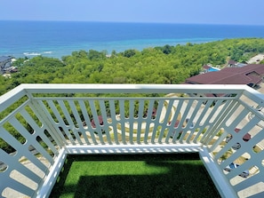 A balcony with a view of the ocean and a lush green landscape. - Royal Oceancrest Panglao 1 (Dauis)