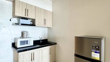 Una cocina con refrigerador de acero inoxidable, microondas y armarios de madera.