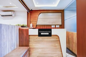 A reception desk with a sign indicating it is company-serviced. There are electrical outlets and a security camera above the desk.