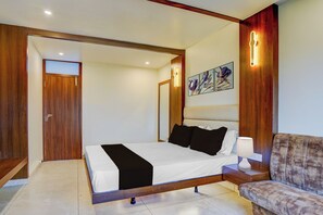 A modern bedroom with a bed, bedside table, and a sofa.