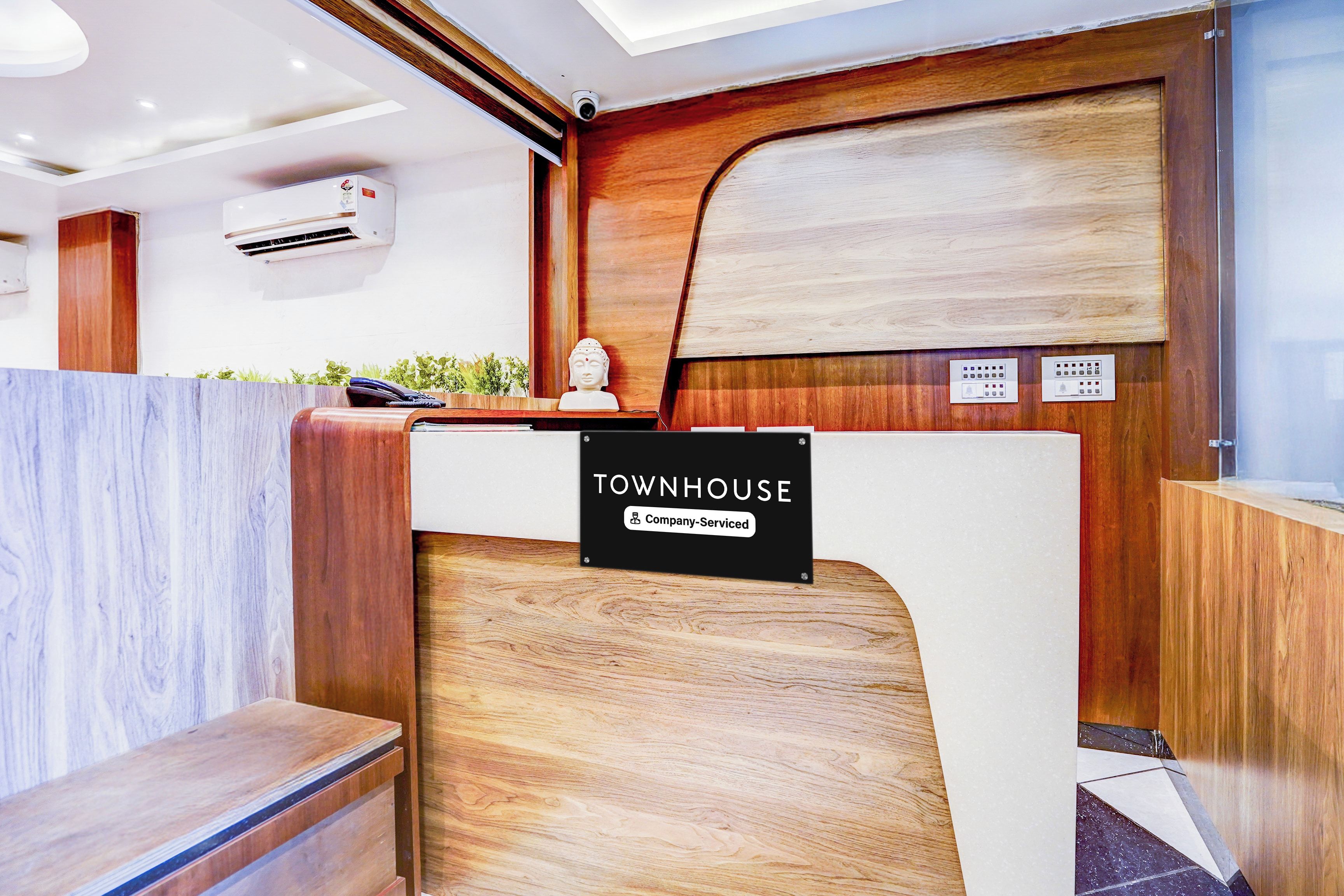 A reception desk with a sign reading 'TOWNHOUSE Company-Serviced' and a wooden reception area.