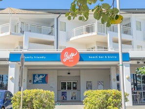 A two-story building with a sign for 'Salt Bar' indicating a family-friendly beach bar and bistro. - The Pool Resort | Studio Pool View Getaway (Kingscliff)