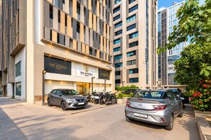 Un hôtel à la façade moderne, avec des voitures garées devant et un ciel dégagé.