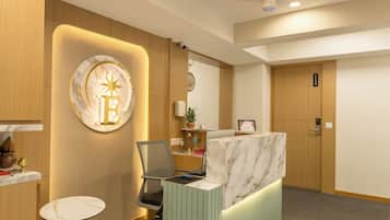A reception area with a marble counter, a green sofa, a small round table, and a ceiling with a decorative pattern.